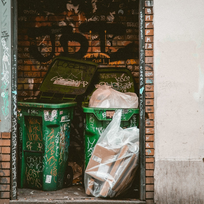 green dumpsters between brick walls