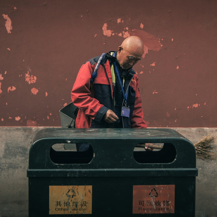 man standing beside trash biin