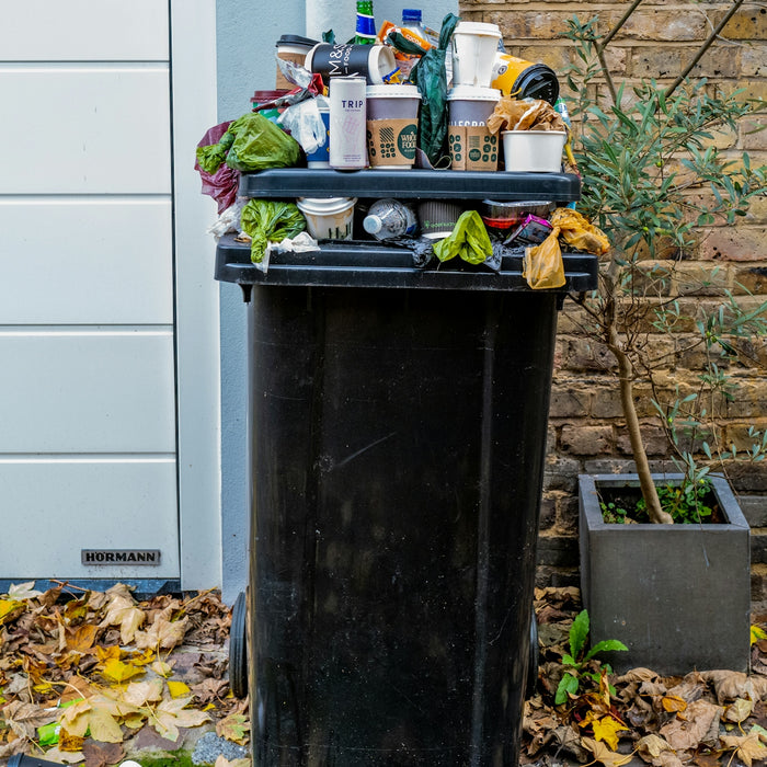 black trash bin with green leaves