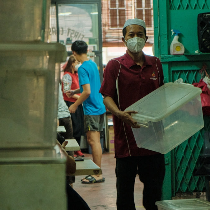 a man wearing a face mask and carrying a plastic container
