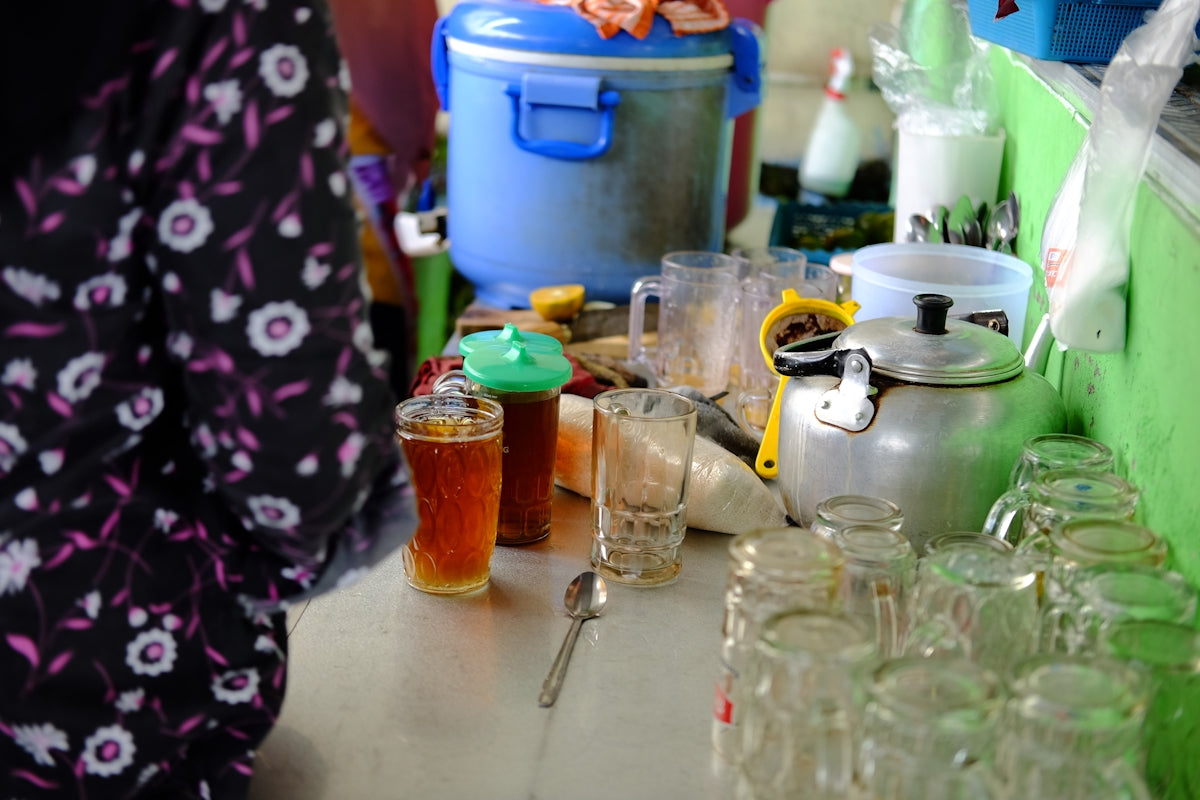a woman standing in front of a counter filled with jars and glasses