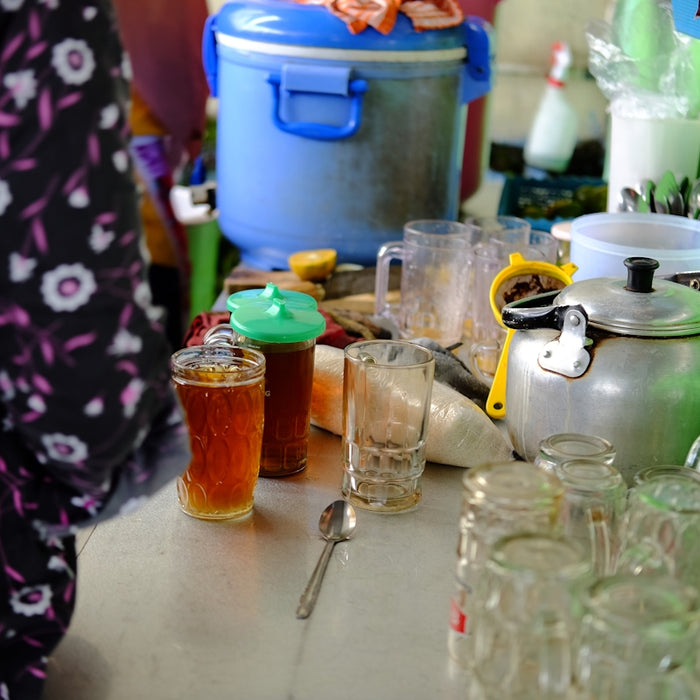 a woman standing in front of a counter filled with jars and glasses