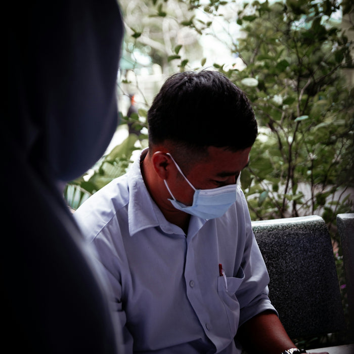 a man wearing a face mask sitting on a bench