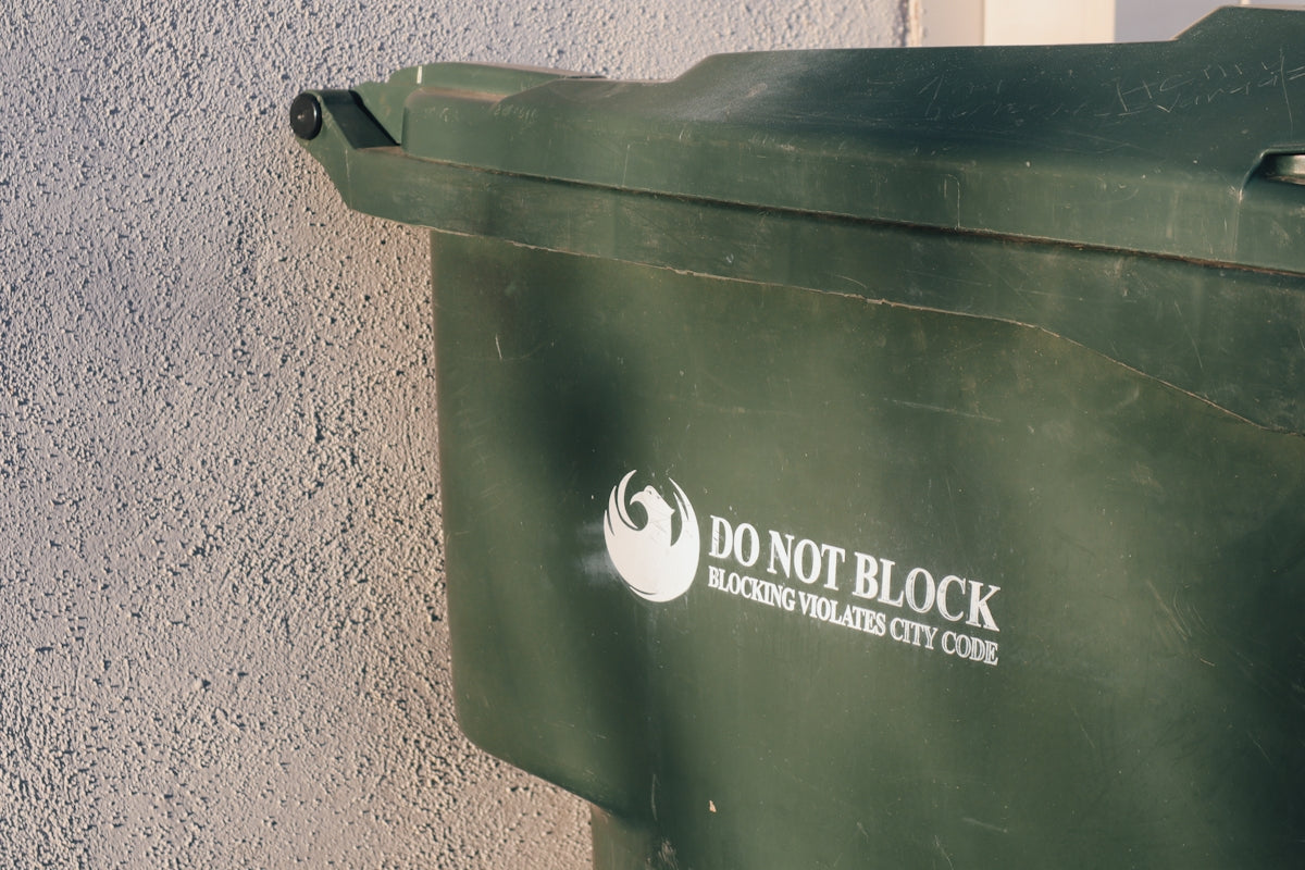 a green trash can with a do not block sticker on it
