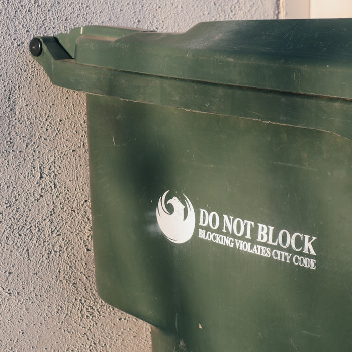 a green trash can with a do not block sticker on it