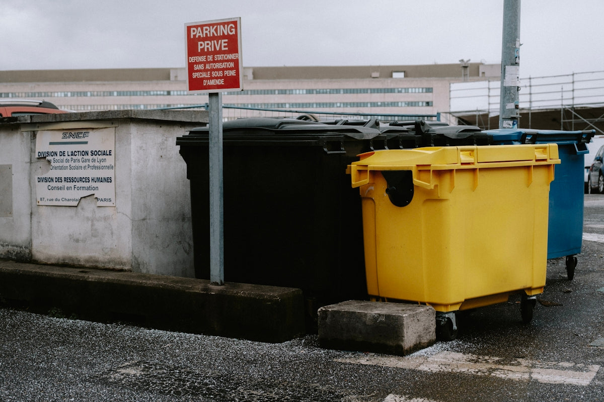 a couple of trash cans sitting on the side of a road