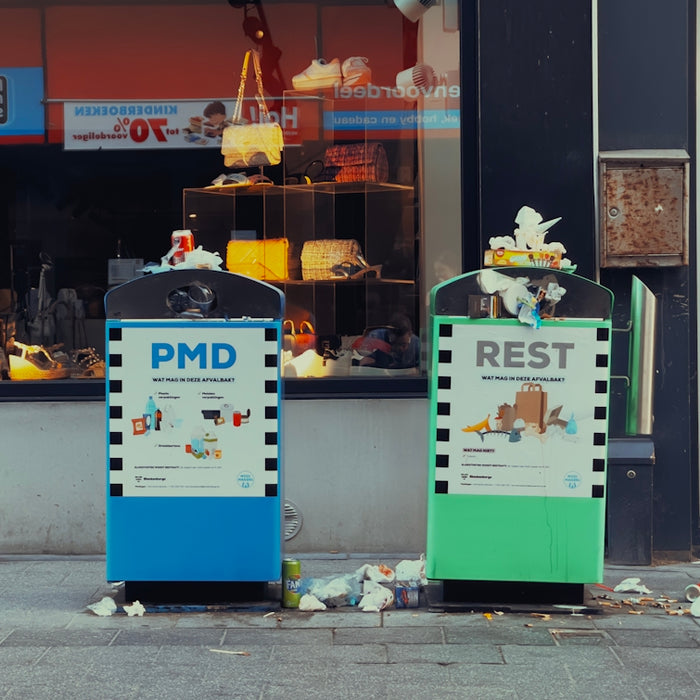 a couple of trash cans sitting on the side of a road