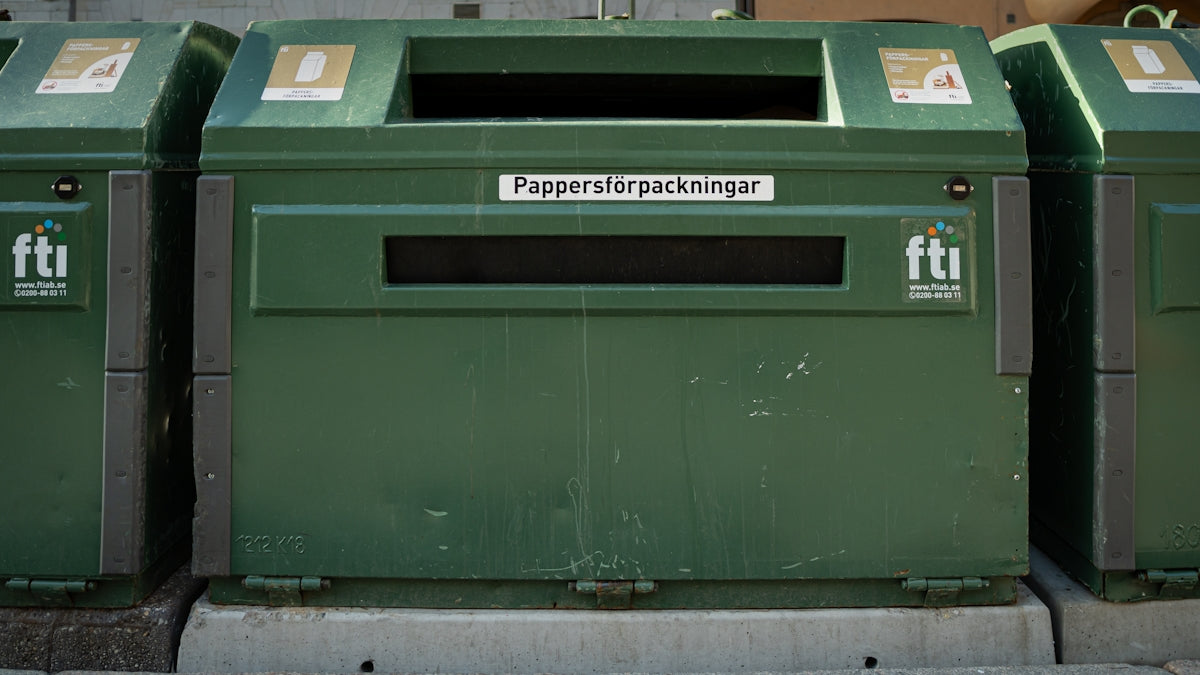 a row of green trash cans sitting next to each other