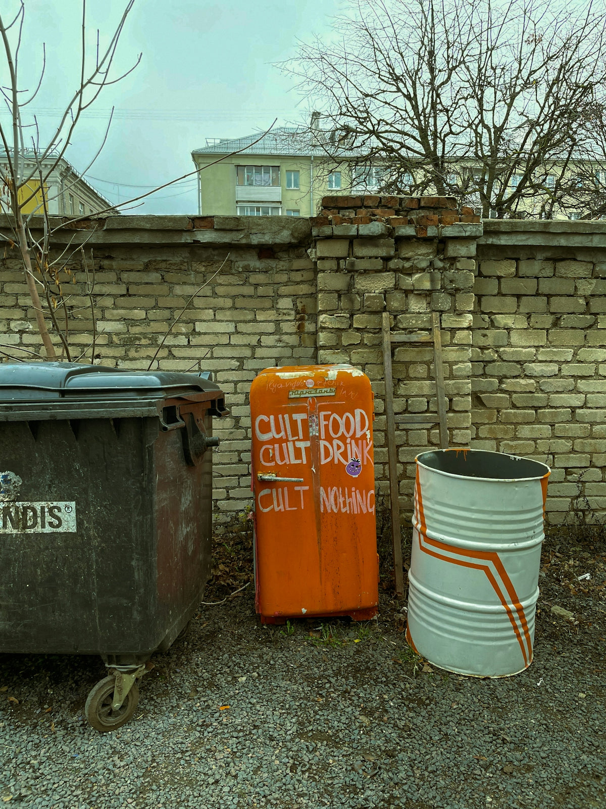 a couple of trash cans sitting next to a brick wall