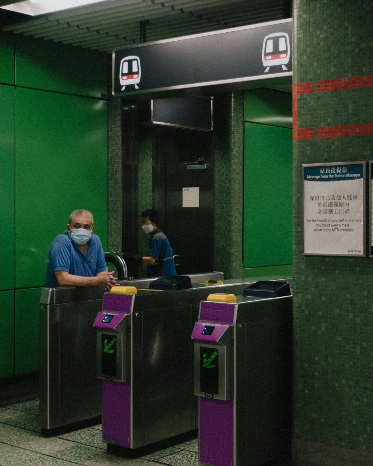 a man wearing a face mask standing next to a green wall
