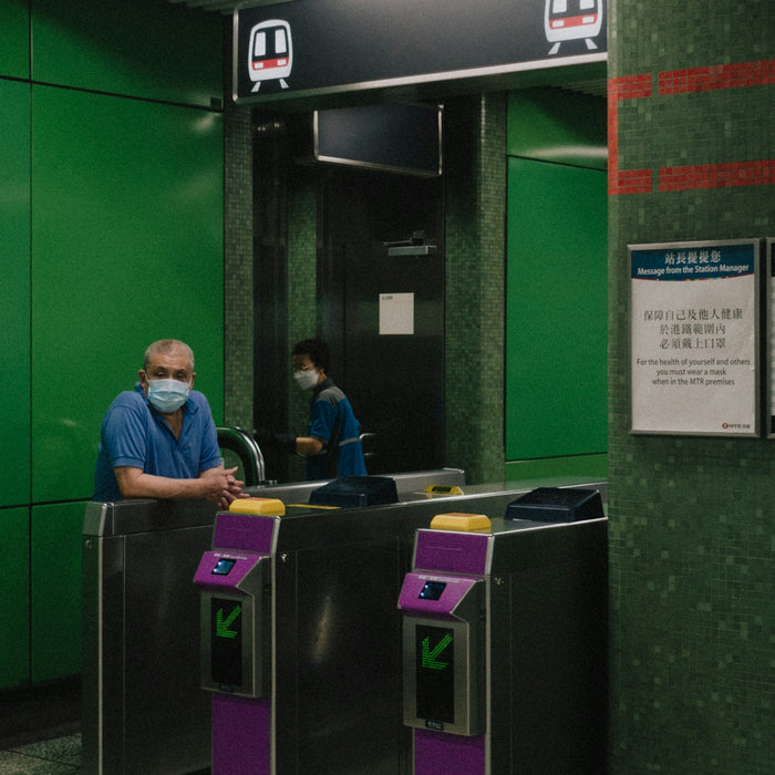 a man wearing a face mask standing next to a green wall