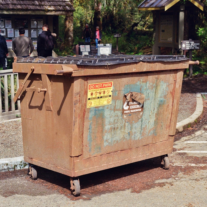 a trash can sitting in the middle of a parking lot