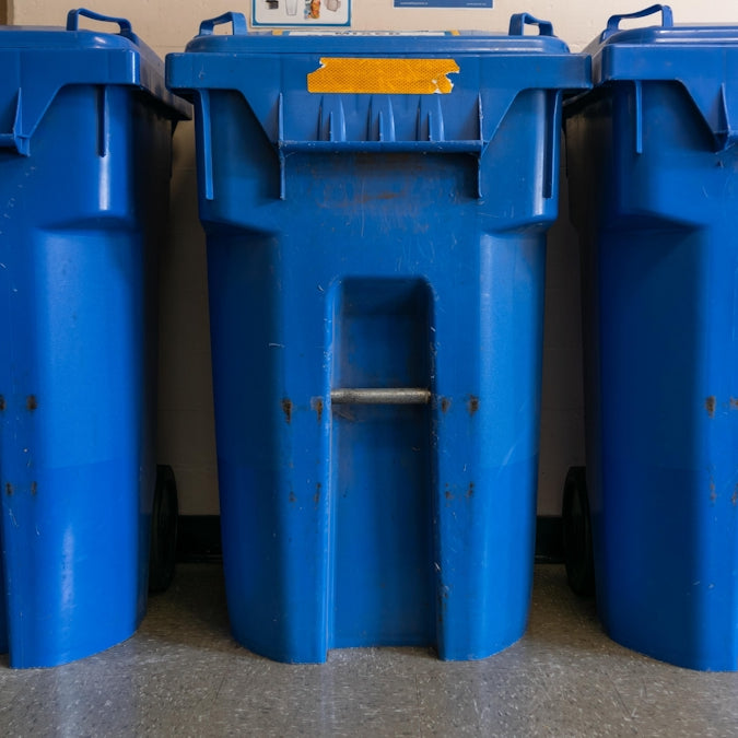 a couple of blue trash cans sitting next to each other