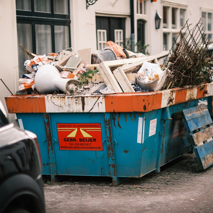 a blue dumpster filled with lots of trash on the side of a road