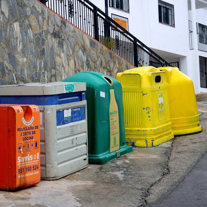 a row of brightly colored trash cans next to a stone wall