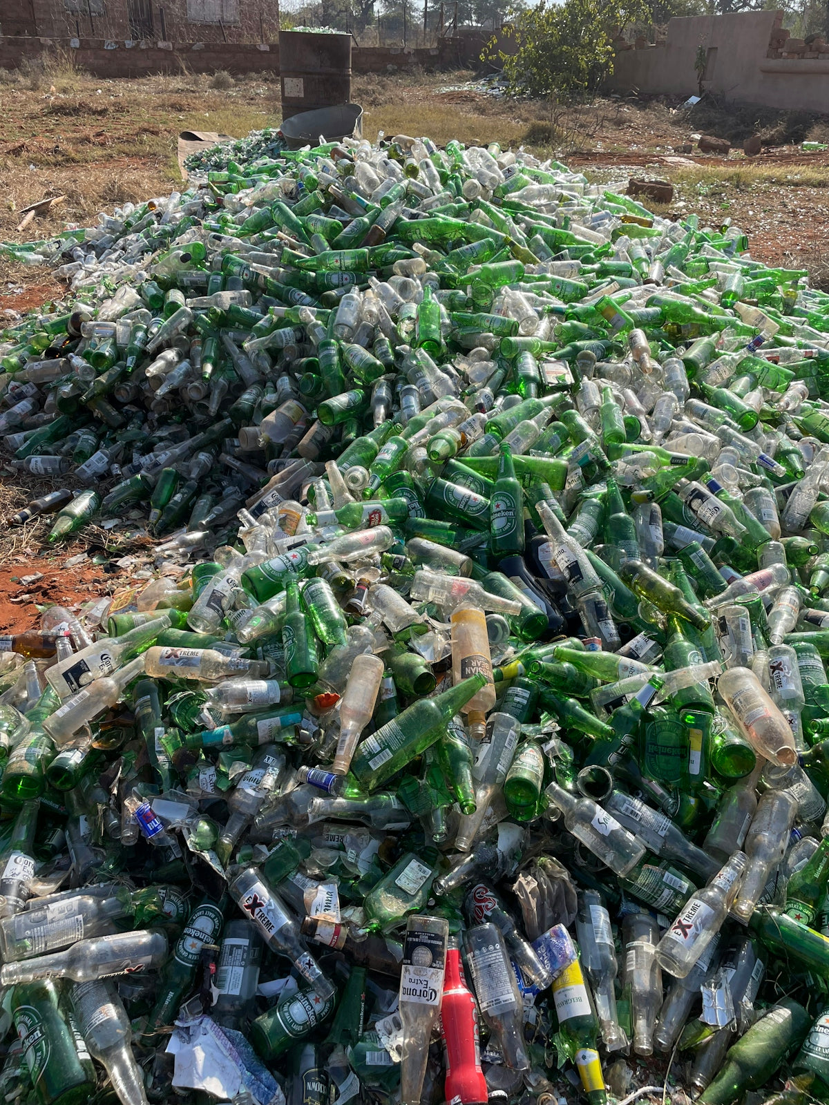 a pile of empty beer bottles sitting on top of a field