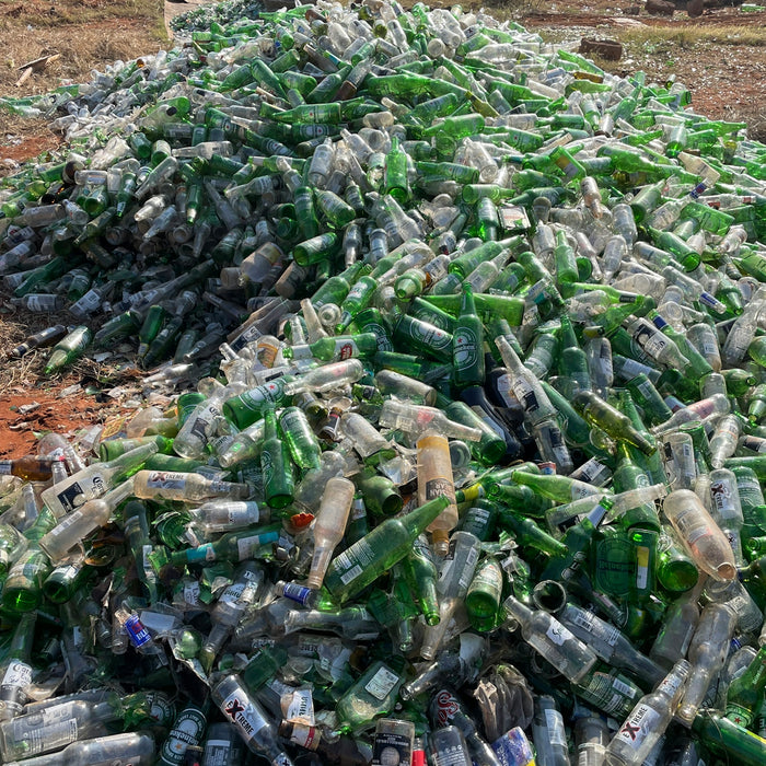 a pile of empty beer bottles sitting on top of a field