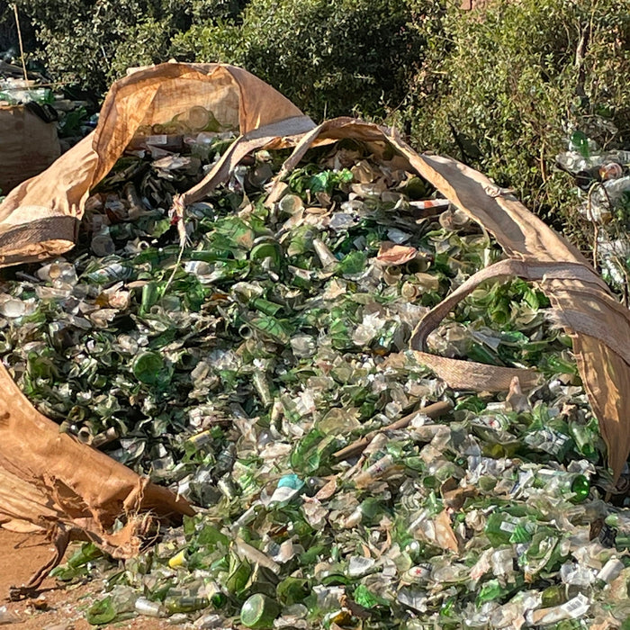 a pile of glass bottles sitting on top of a dirt field