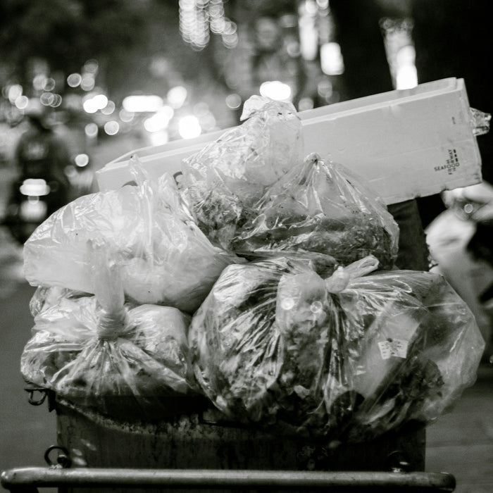 a black and white photo of a trash can filled with bags