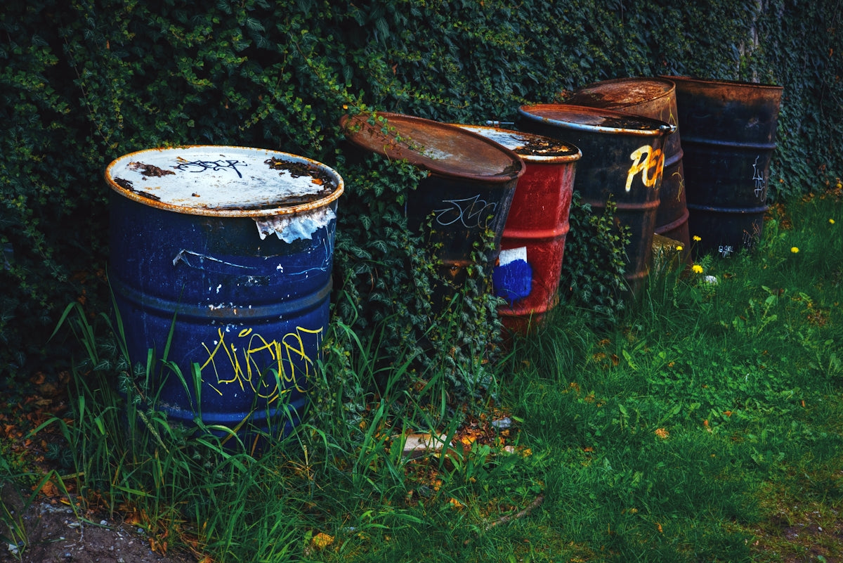 a row of trash cans sitting on top of a lush green field