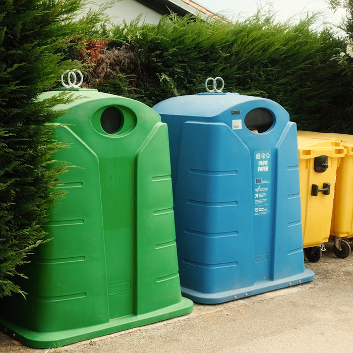 A row of trash cans sitting next to a bush