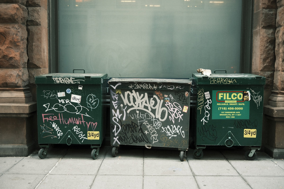 A row of trash cans sitting on the side of a building