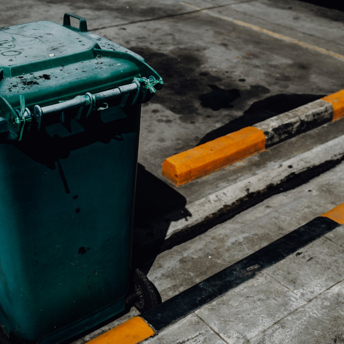 Trash can and parking bumpers on pavement.