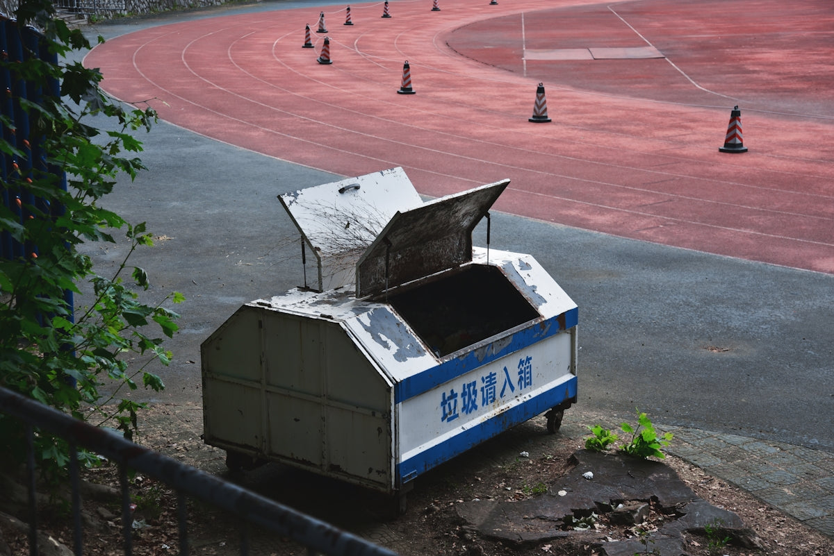 A trash cart sits near a running track.