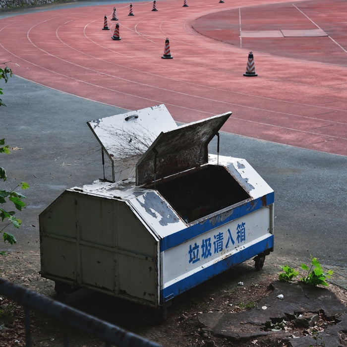 A trash cart sits near a running track.