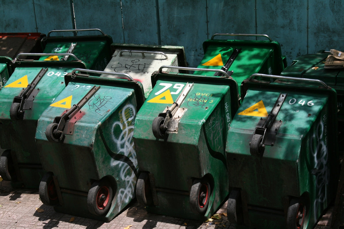 Several green wheeled trash bins are lined up.