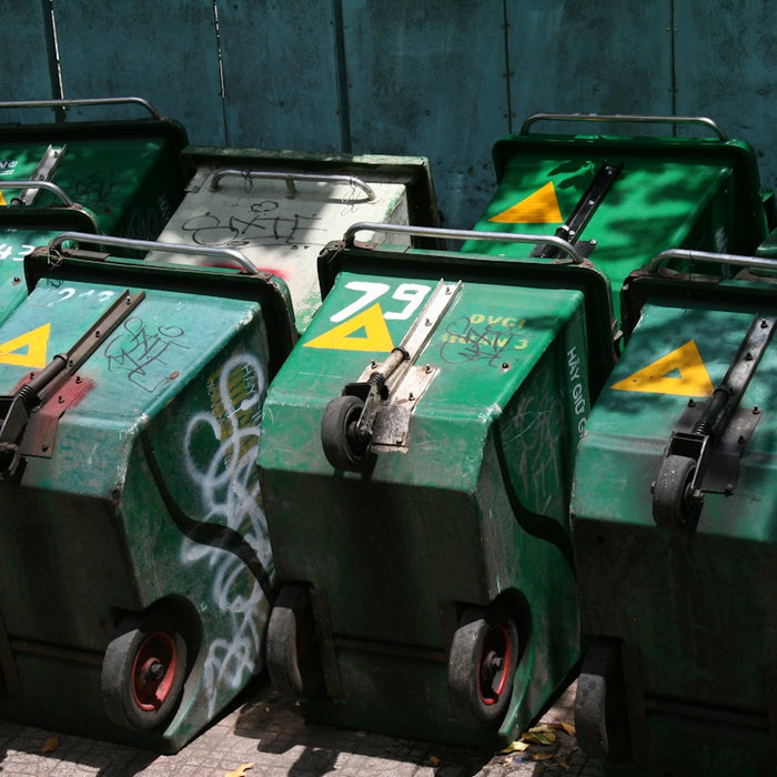 Several green wheeled trash bins are lined up.
