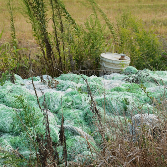 Green netting piled with a bucket behind it.