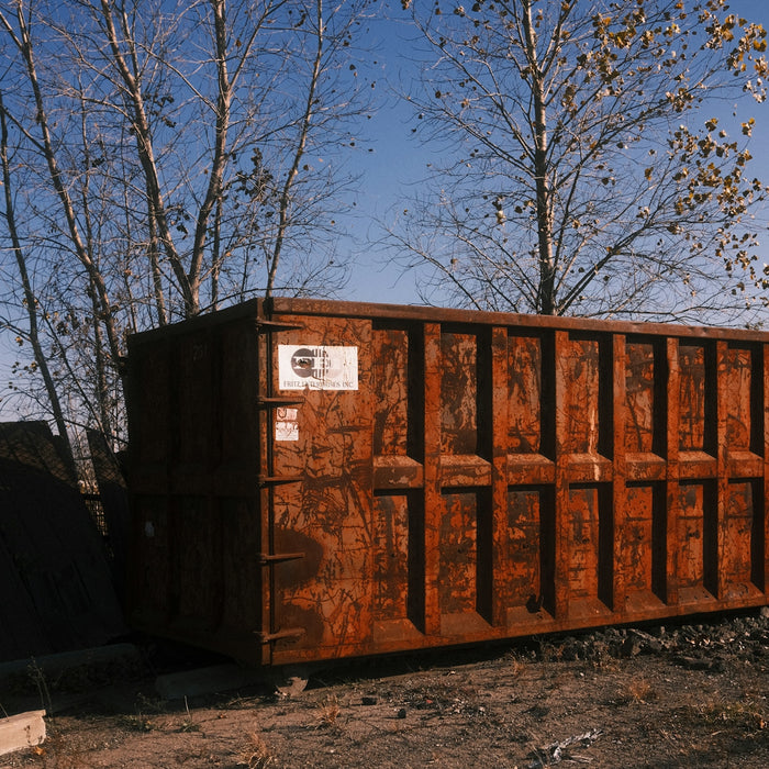Rusty industrial dumpster in an outdoor lot.