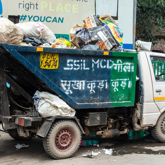 A garbage truck filled with trash on a street.