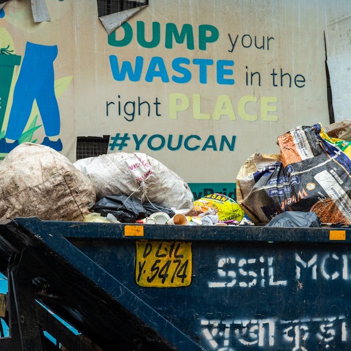 Overflowing dumpster with trash and a sign